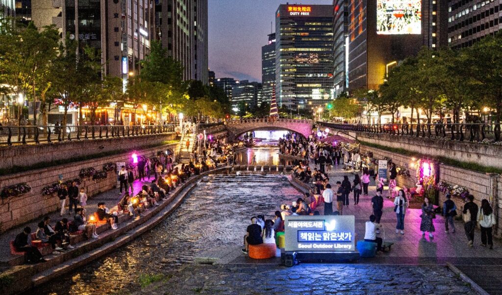 An image of an event scene in a public area with a river and people